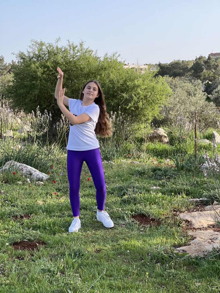 Child dancing outdoors in a green field