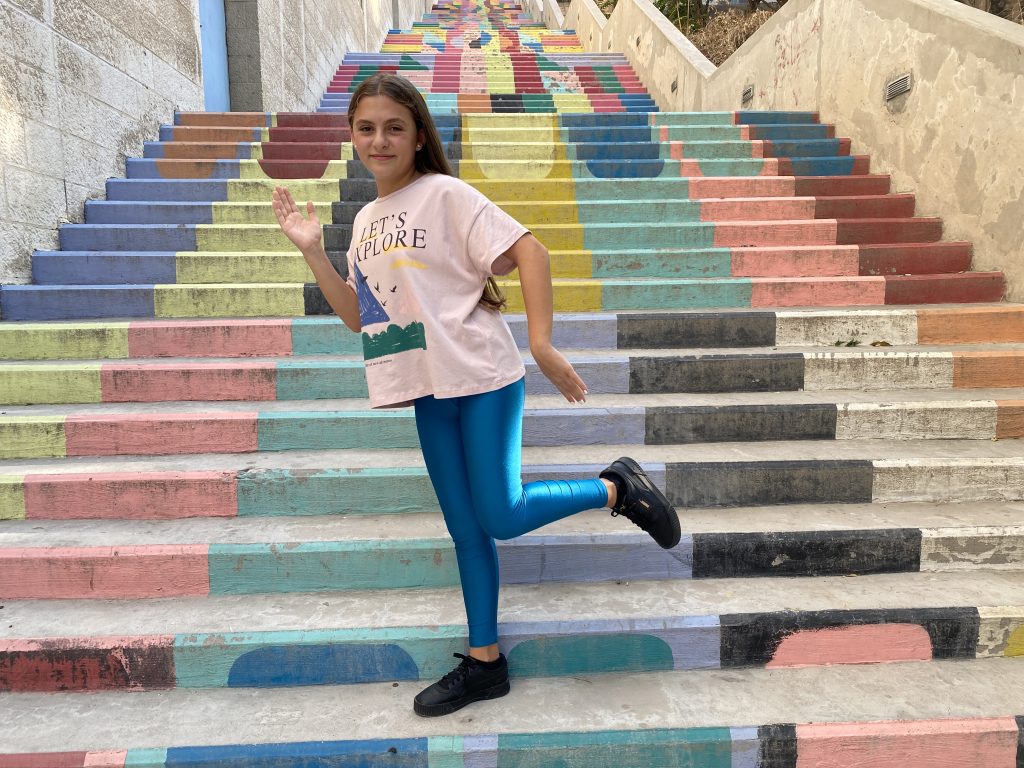 Child dancing on colourful painted stairs